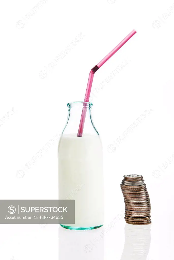 Milk in a bottle with a straw beside a stack of coins