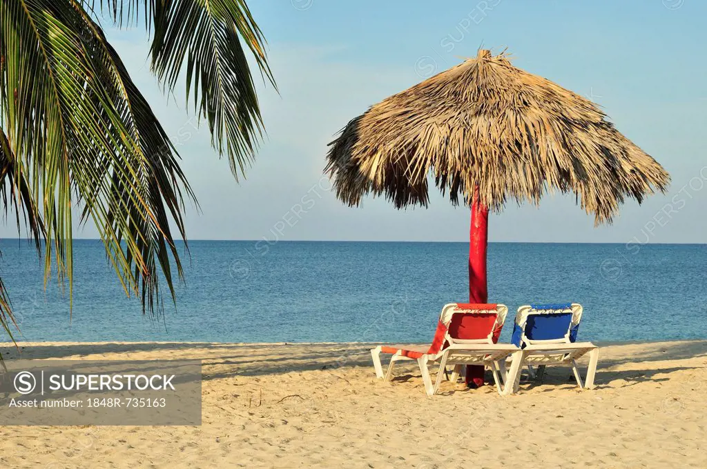 Empty sunbeds under a parasol on the beach of Playa Ancón near Trinidad, Cuba, Caribbean