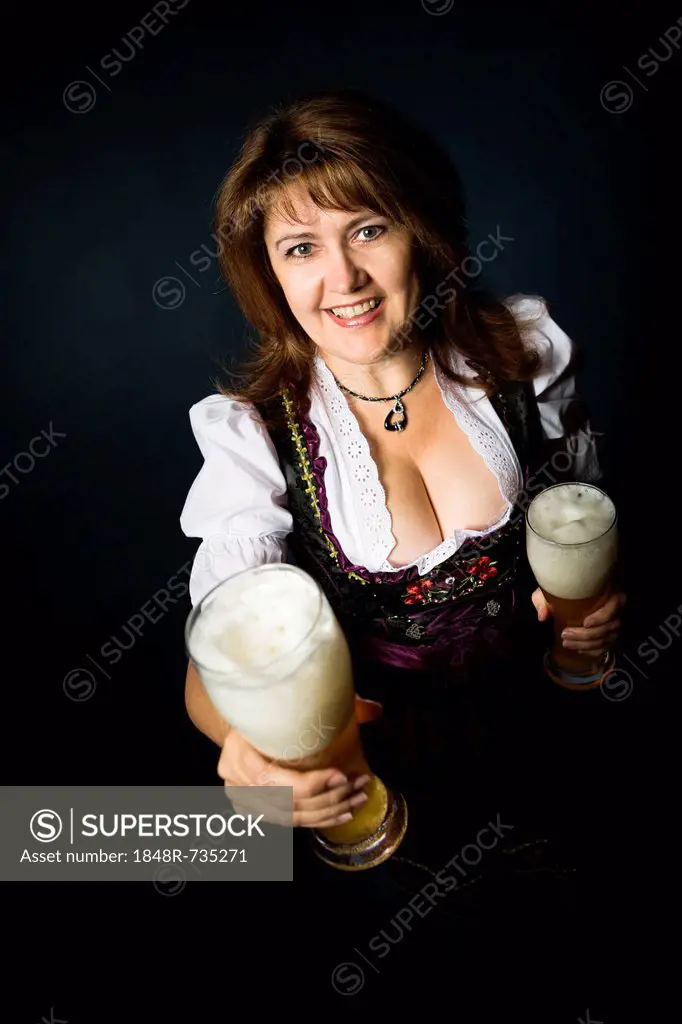 Bavarian woman dressed in traditional dirndl, holding beer glasses