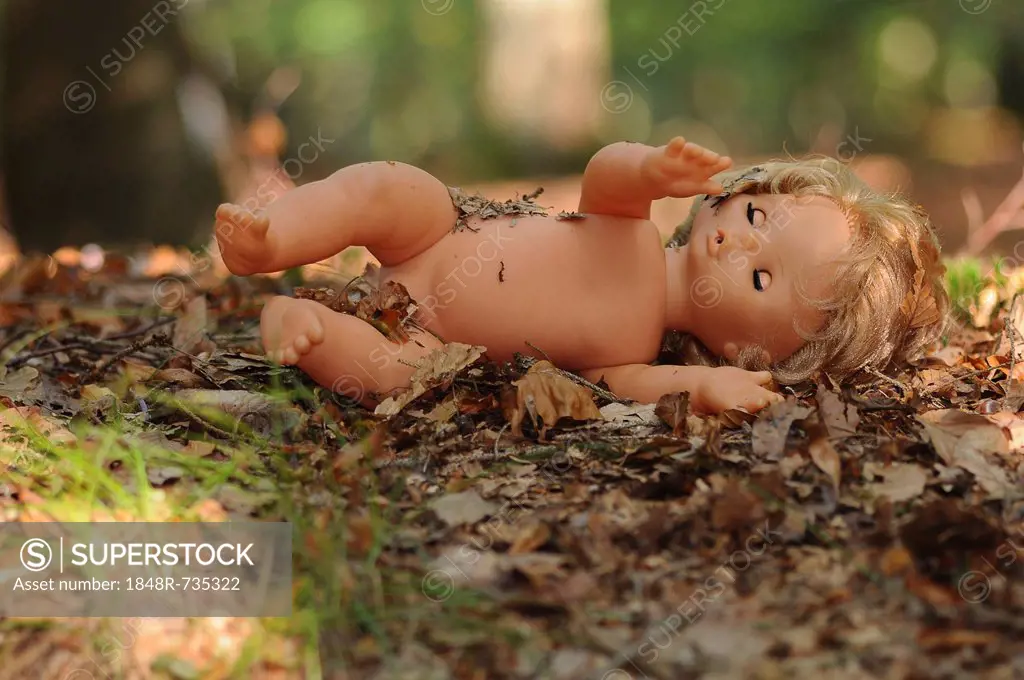 Naked doll in the woods, symbolic image for child abuse, kidnapping