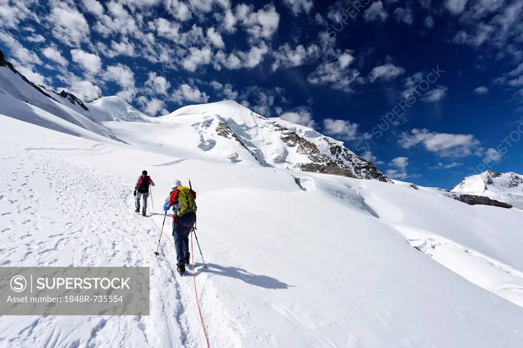 Mountaineers climbing Piz Palue mountain, glacial landscape, the summit of Piz Palue mountain at the back, Piz Bernina mountain with Biancograt ridge ...