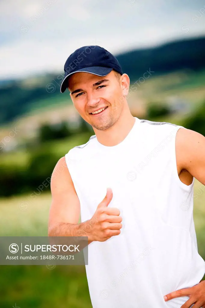 Athletic young man showing thumbs up, fields near Coburg, Bavaria, Germany, Europe