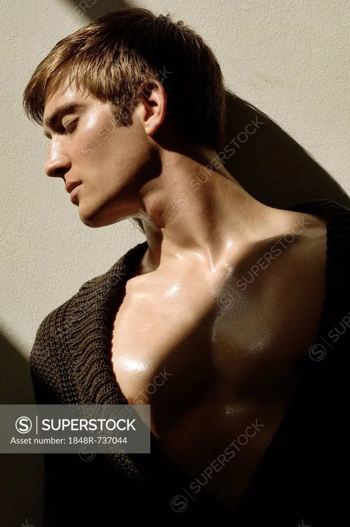 Portrait of a young man leaning on a wall in the sunlight