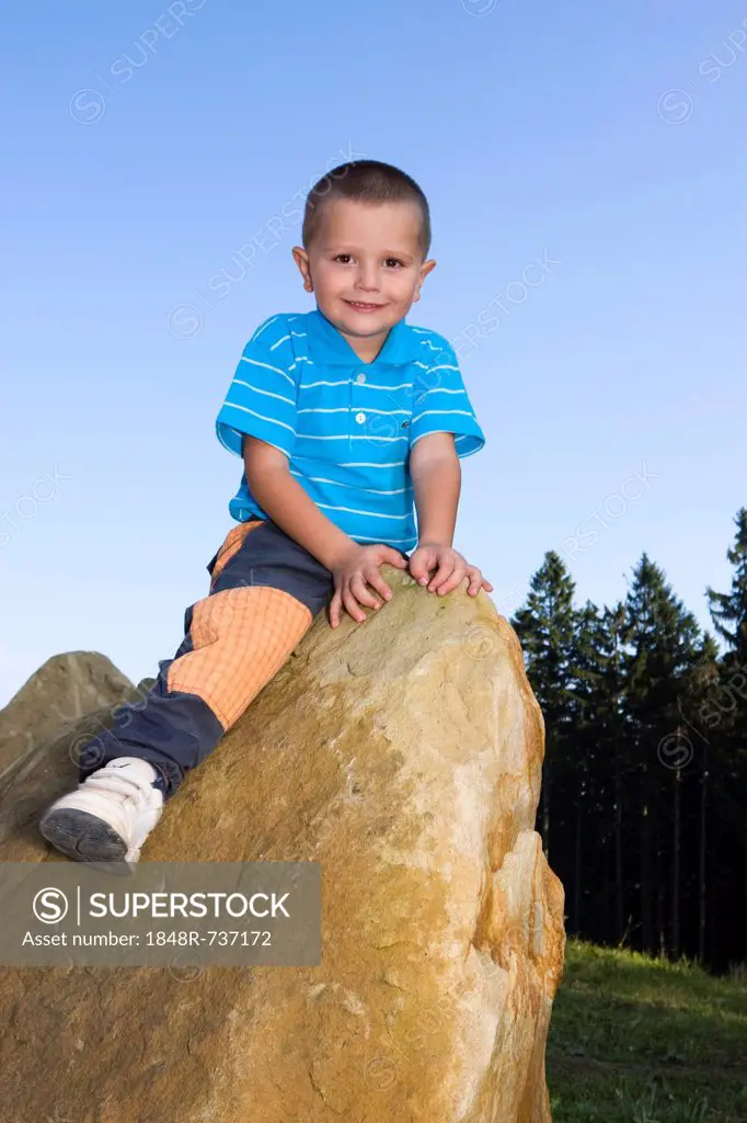 Boy, 4 years, sitting on a rock