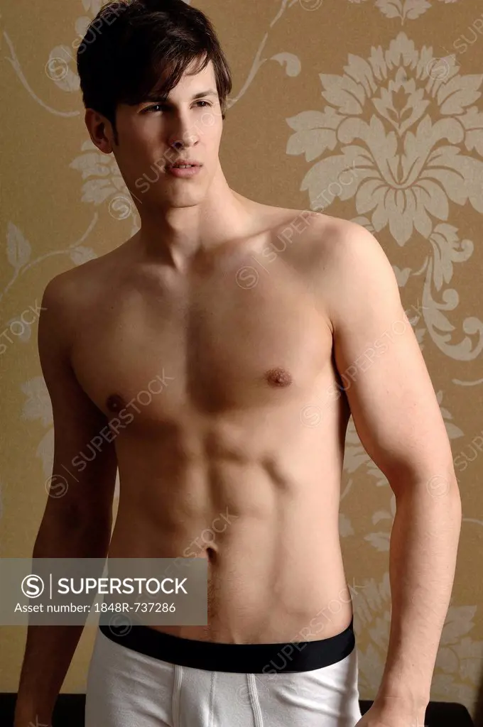 Young man wearing underwear standing in front of nostalgic wallpaper