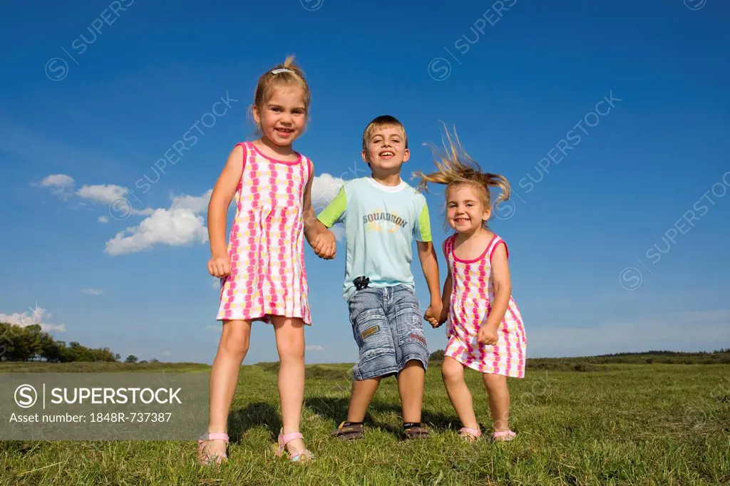 Twin girls, 3 years, and their brother, 7 years, outdoors