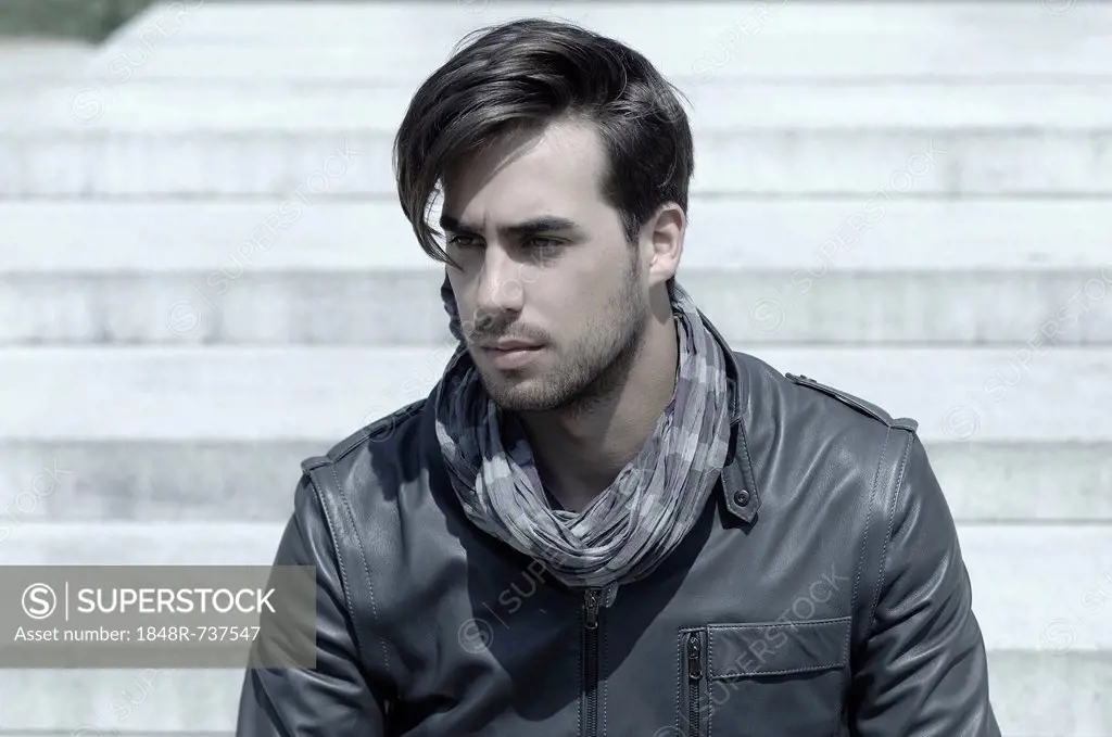 Young man wearing a leather jacket in front of an open staircase, portrait