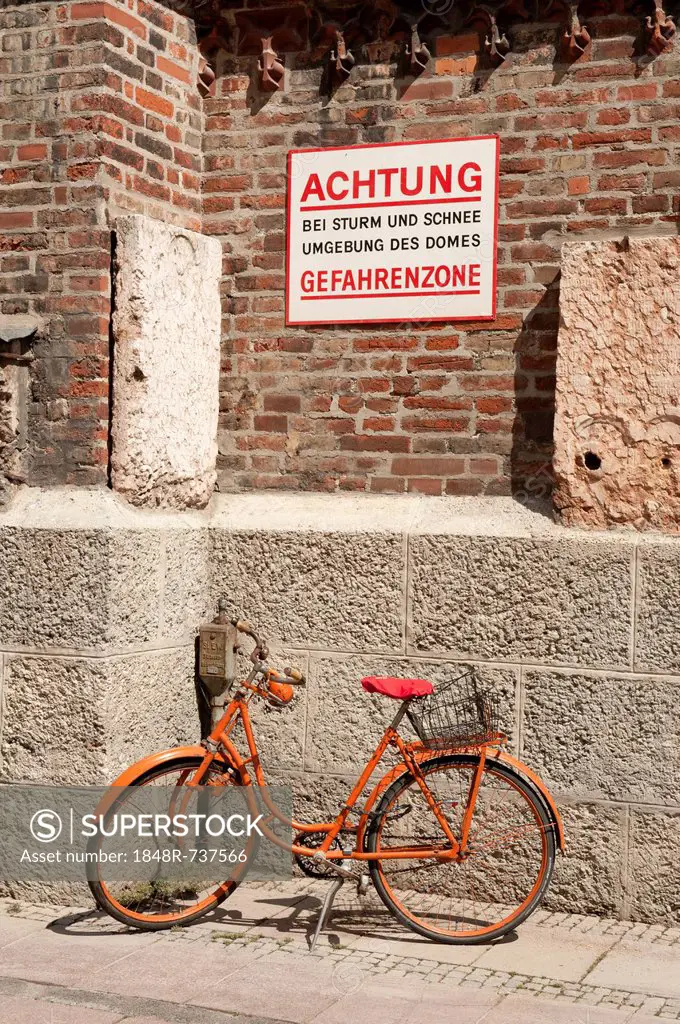 Orange bike in the danger zone during storms and snow on a wall, Frauenkirche or Church of Our Lady, Munich, Upper Bavaria, Bavaria, Germany, Europe