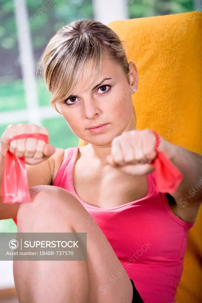 Young woman doing exercises with rubber strap