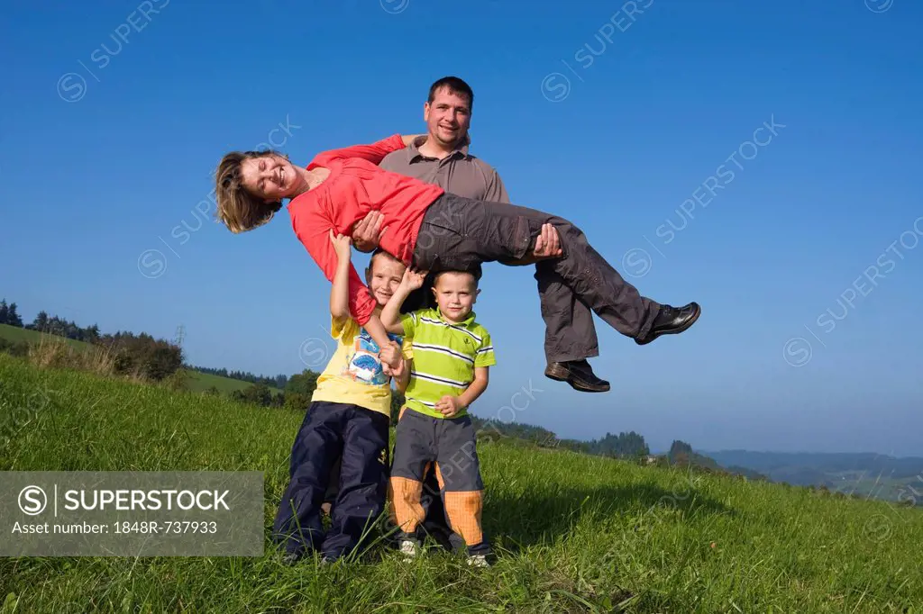 Family, father, 36 years, mother, 30 years, children, 6 and 4 years, playing in a meadow