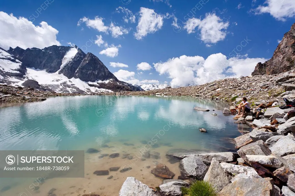 Hiker resting at a lake below the Tschenglser Hochwand above the Duesseldorf Hut in Solda, with Vertainspitze Mountain at the rear, Solda Valley, Alto...
