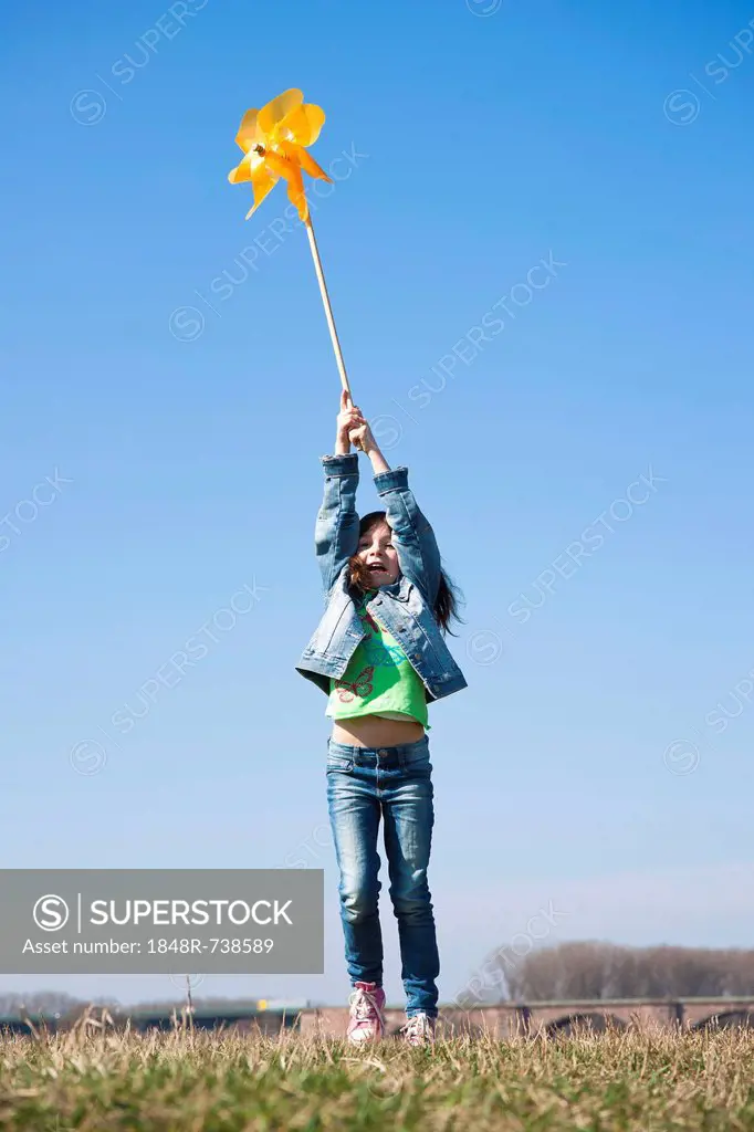 Girl holding up a pinwheel in a field
