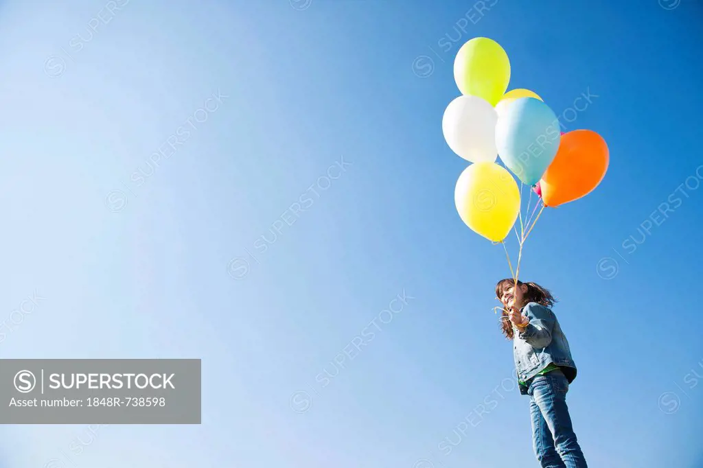 Girl holding many colourful balloons in her hand