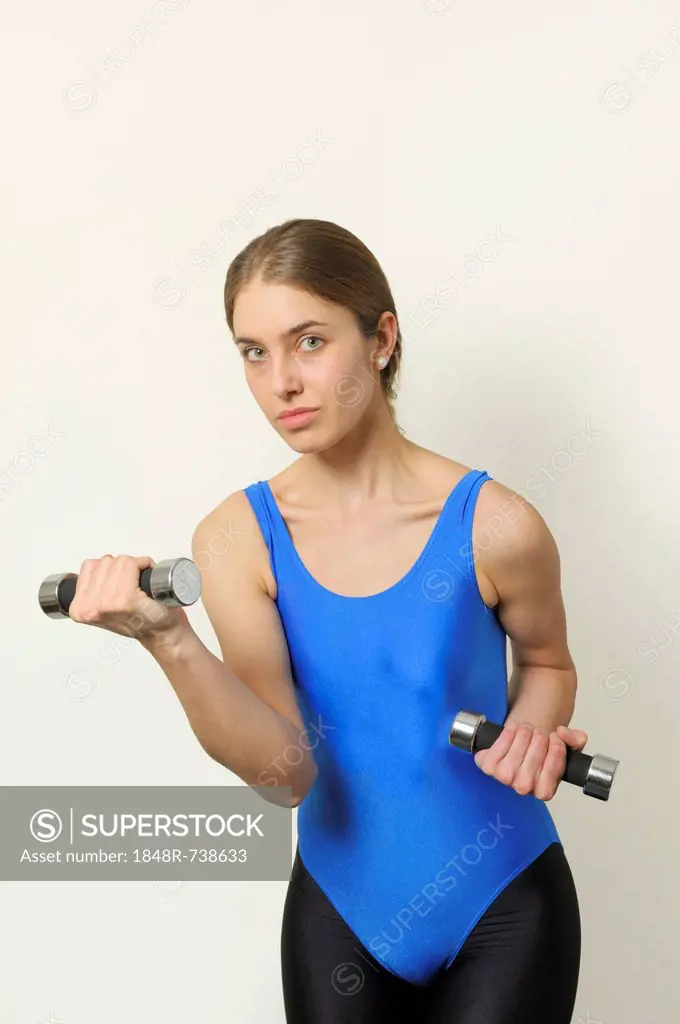 Young woman wearing a shiny spandex leotard and leggings, fashionable in the early 1990's, doing a workout with dumbbells