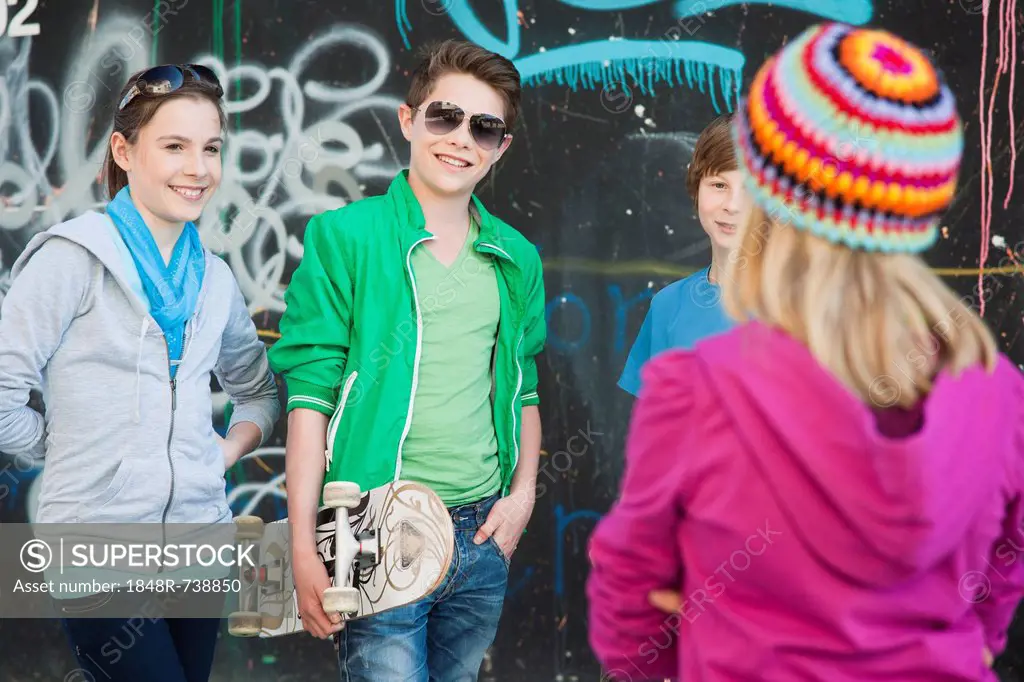 Teenagers standing in front of a wall with graffiti