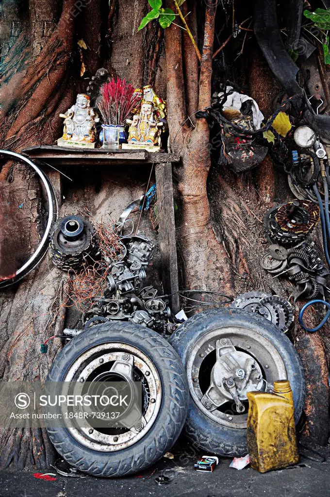 Buddhist altar surrounded by replacement parts of a motorcycle repair shop in Phnom Penh, Cambodia, Southeast Asia