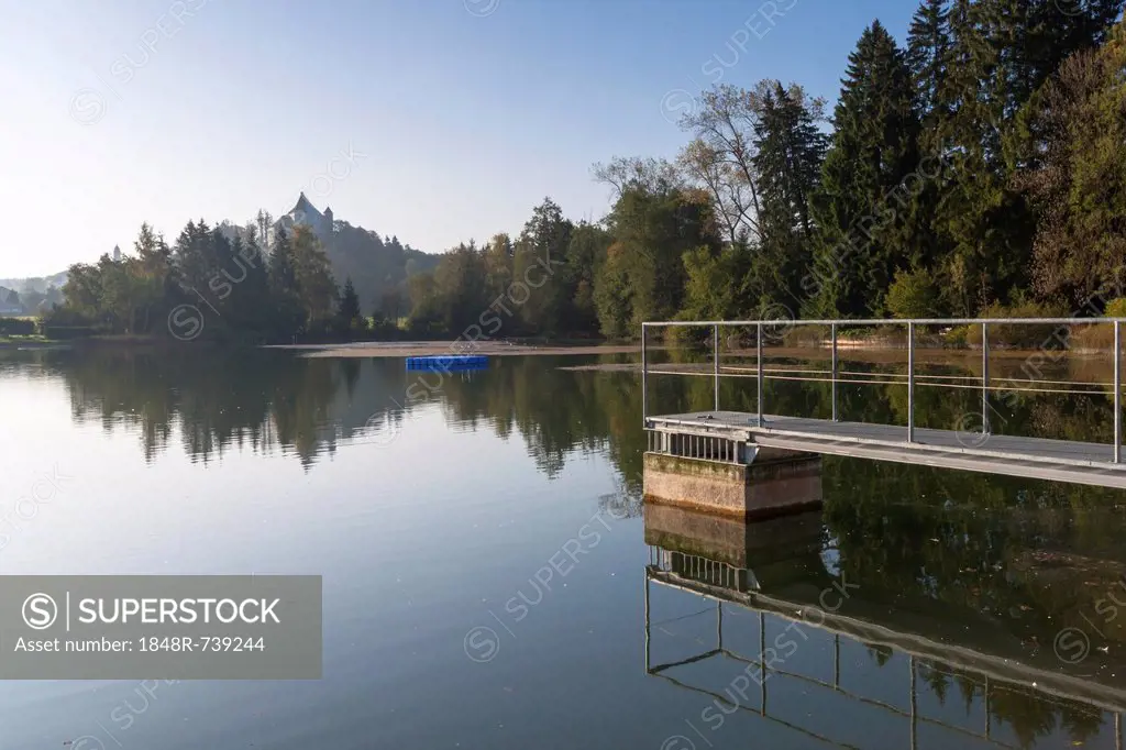 The Hohes Schloss castle of Bad Groenenbach is reflected in the natural outdoor swimming pool Bad Clevers in the morning light, Allgaeu, Bavaria, Germ...