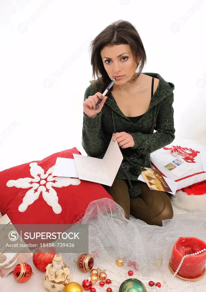 Young woman writing Christmas cards between Christmas decorations
