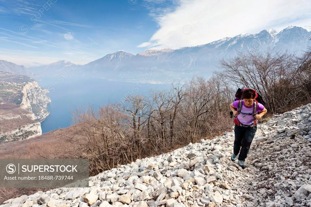 Hiker during the ascent from Campione to Madonnina di Monte Castello, ovrlooking Lake Garda and the village of Malcesine, Brescia, Italy, Europe