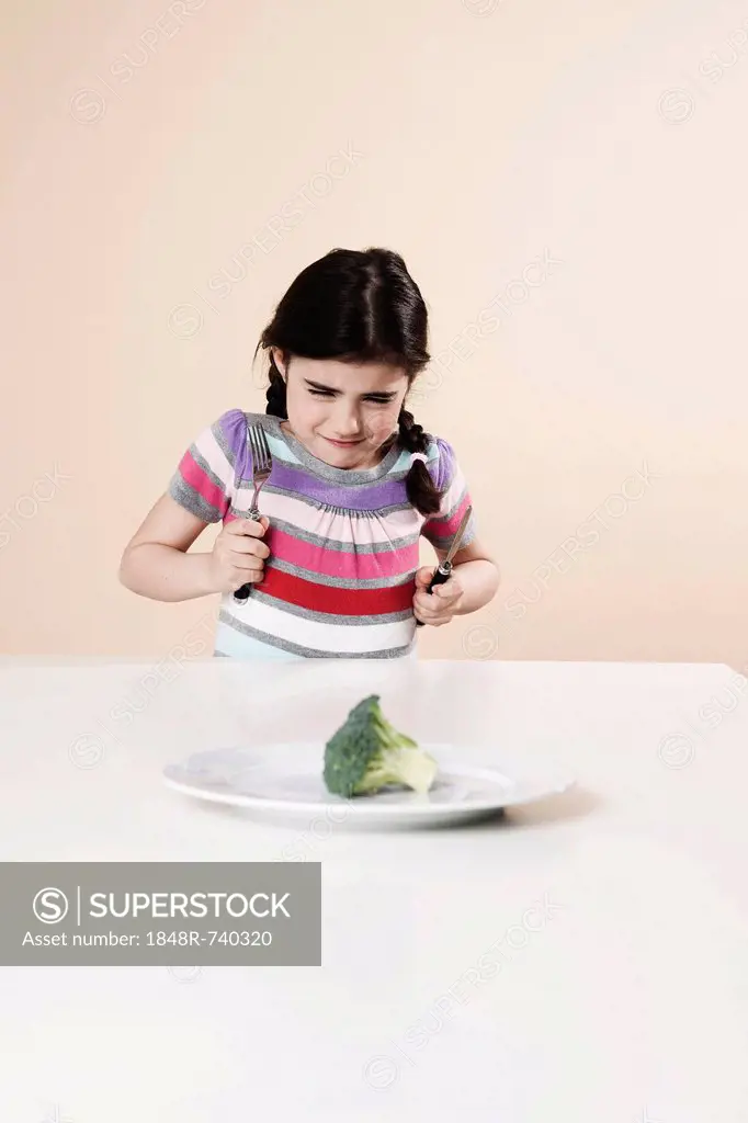 Girl looking with disgust at the broccoli on her plate