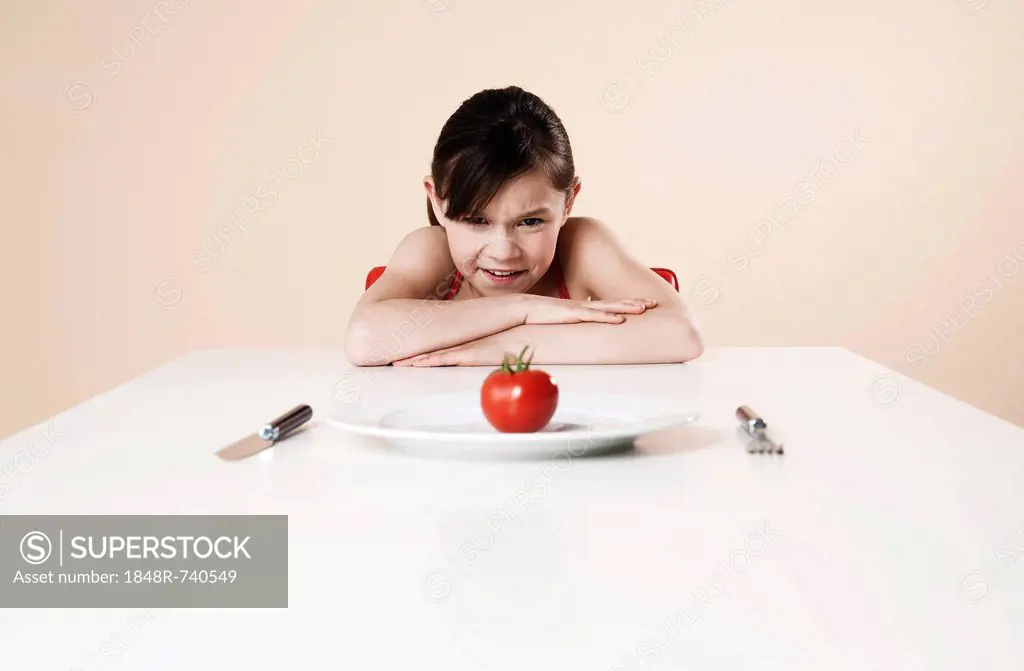 Girl looking disgustedly at a tomato
