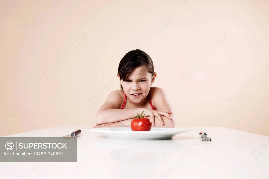 Girl looking disgustedly at a tomato