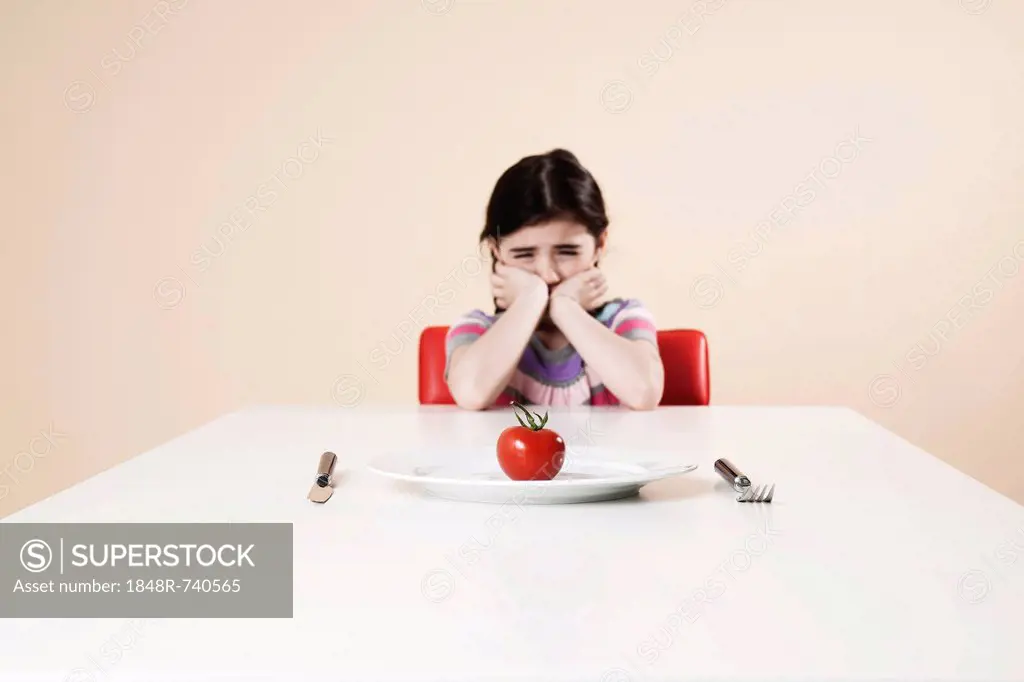 Girl looking with disgust at the tomato on her plate