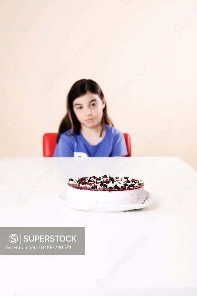 Girl sitting pensively in front of a cake