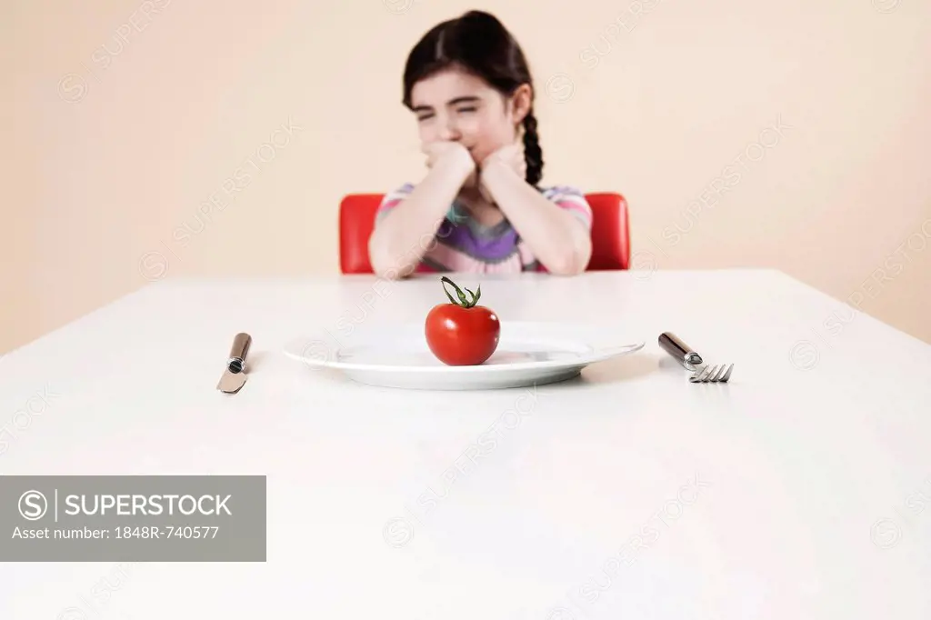 Girl looking with disgust at the tomato on her plate