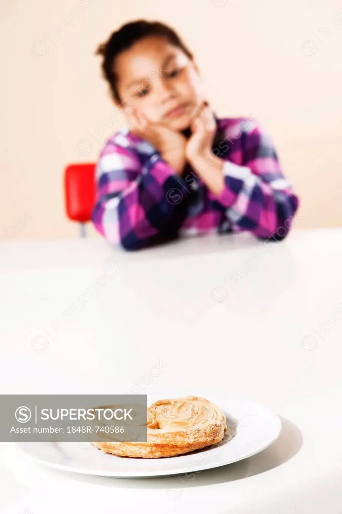 Girl considering whether to eat a piece of sweet pastry