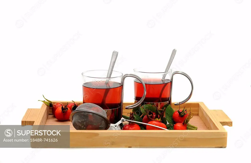 Two glasses of rose hip tea and rose hips on a wooden tray