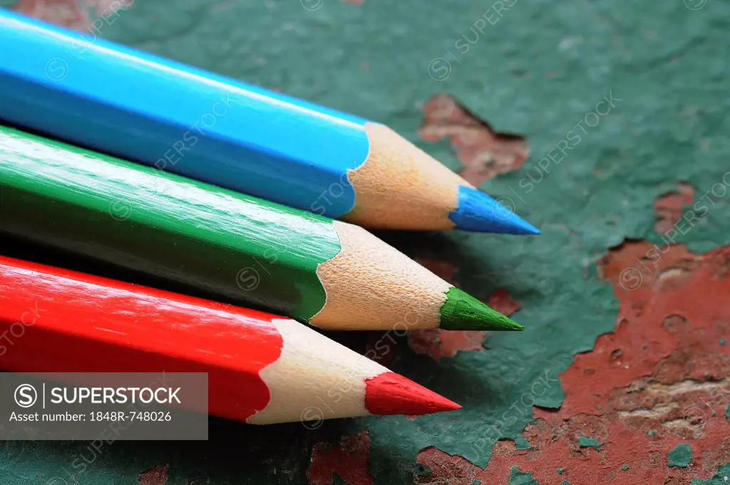 Wooden coloured pencils, red, green and blue on an old wooden board