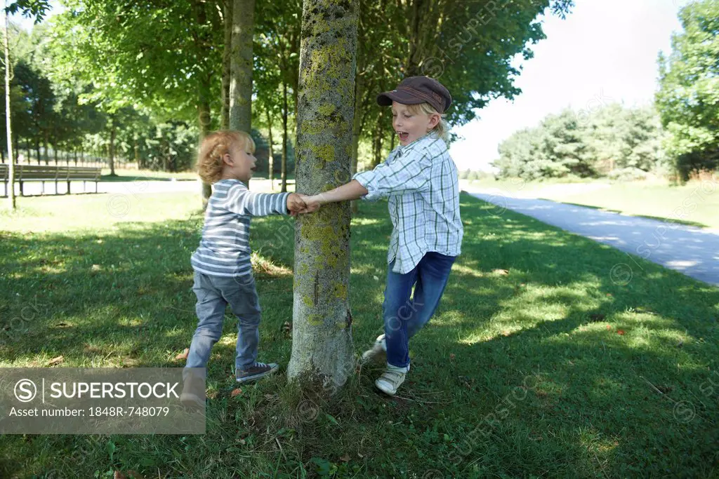 Two boys dancing around a tree