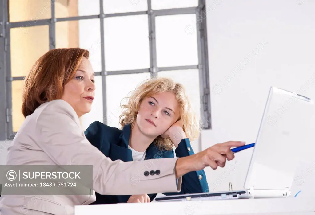 Manager working in an office with a trainee at the computer