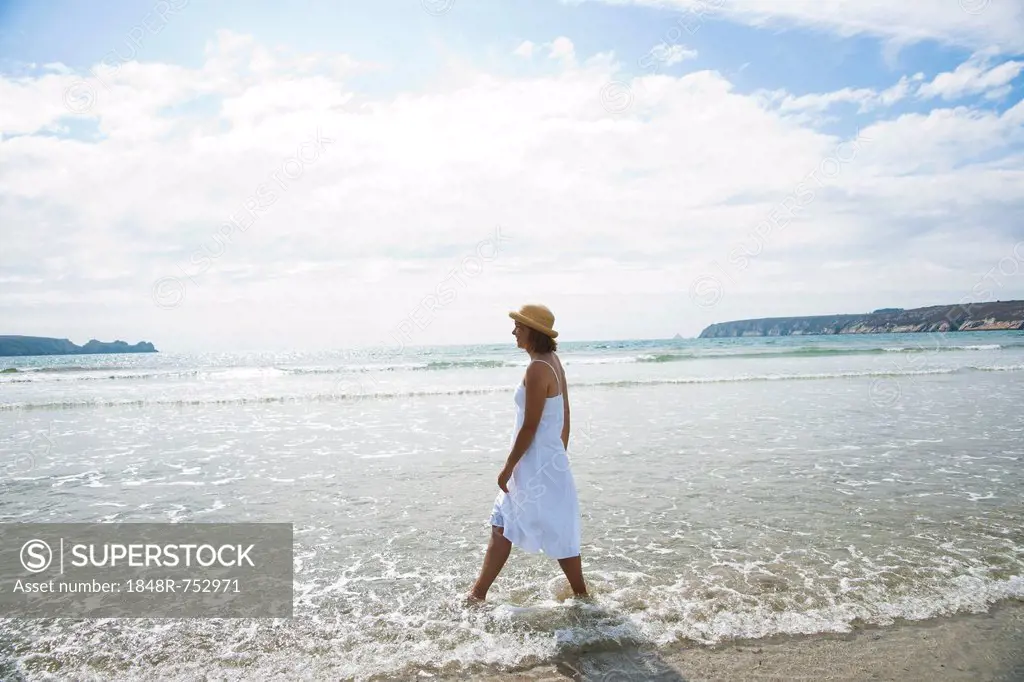 Woman walking through small waves on a beach