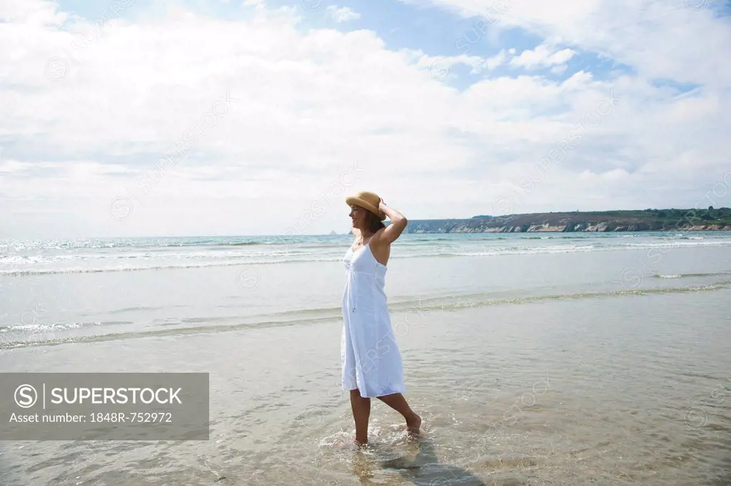 Woman walking through small waves on a beach