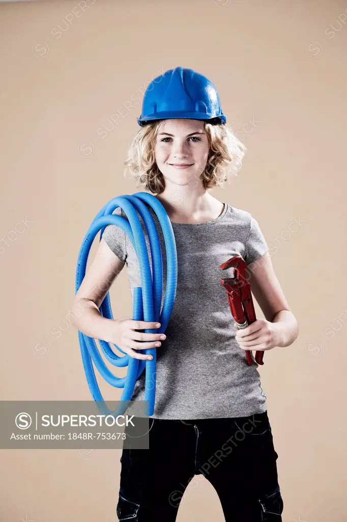 Girl wearing a hard hat and holding a pipe wrench