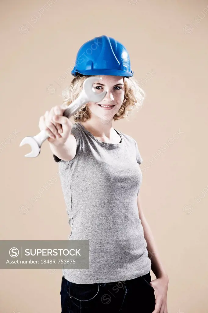 Girl wearing a hard hat and holding a spanner