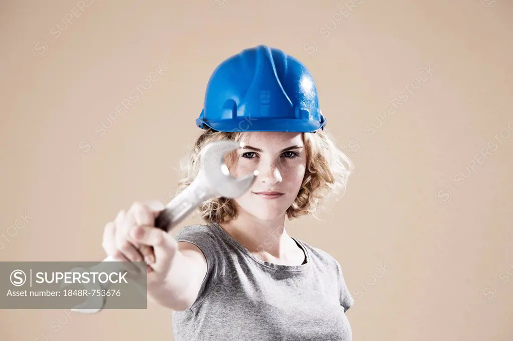 Girl wearing a hard hat and holding a spanner