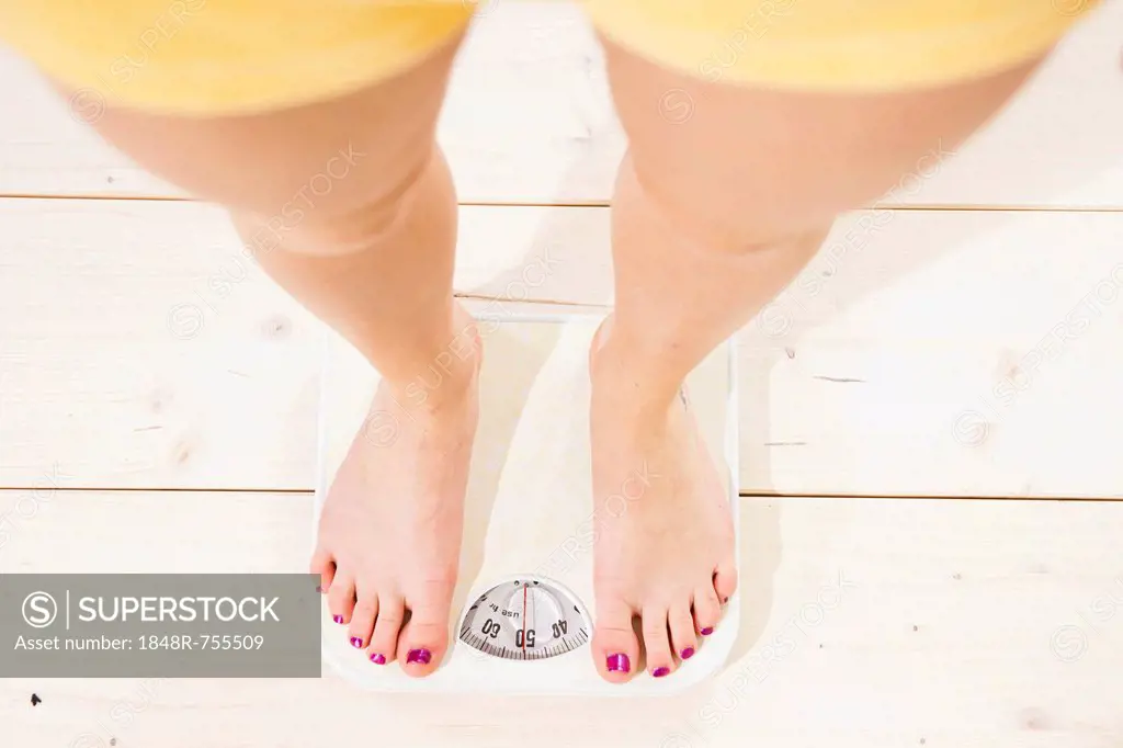 Young woman standing on a scale and checking her weight