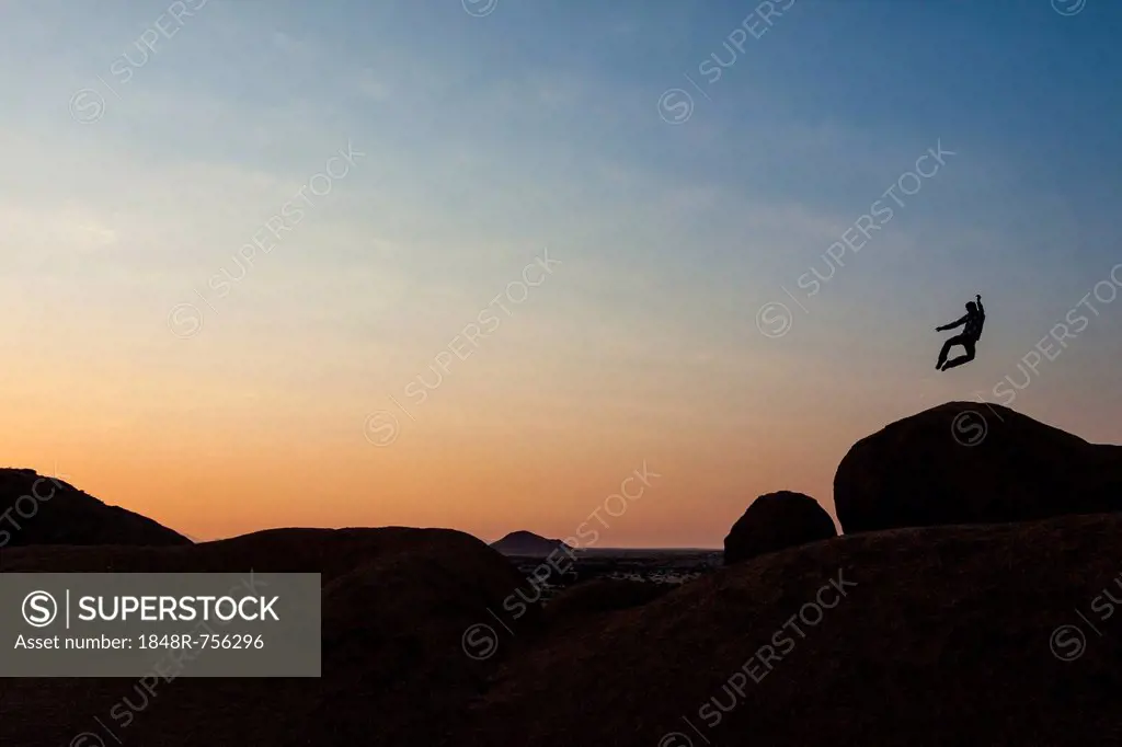 Young man jumping, granite rocks, near Spitzkoppe granite peaks, Damaraland, Namibia, Africa