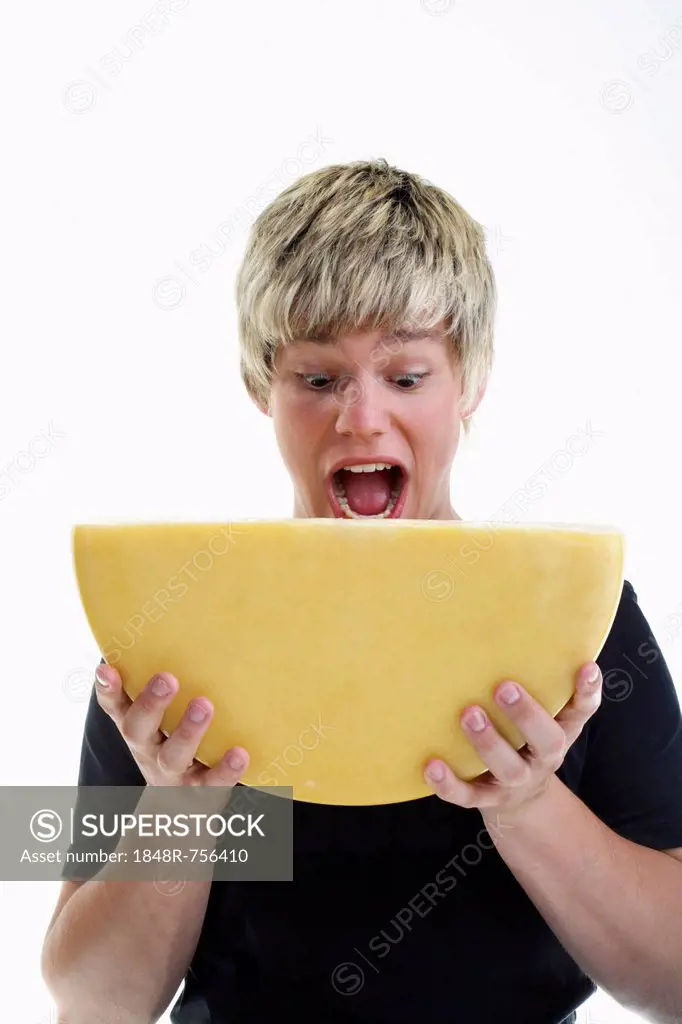 Smiling young man holding half a wheel of cheese