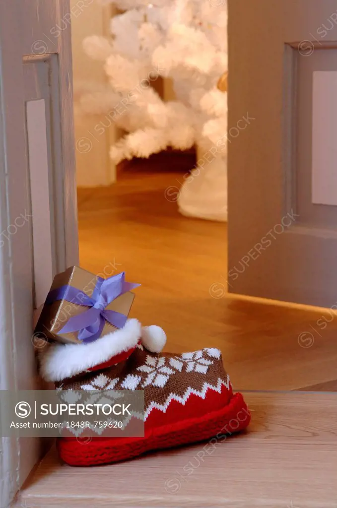 Woolly slipper with Norwegian pattern and present outside an open door