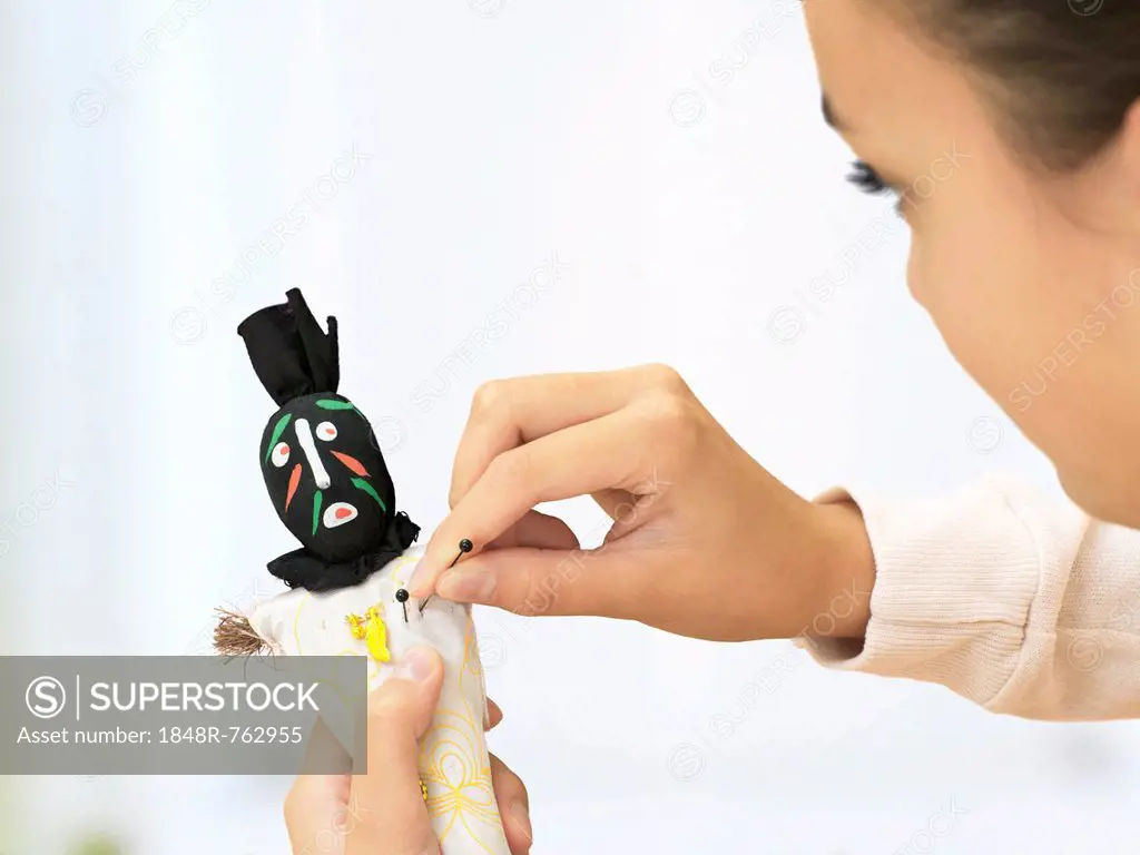 Woman sticking needles into a voodoo doll