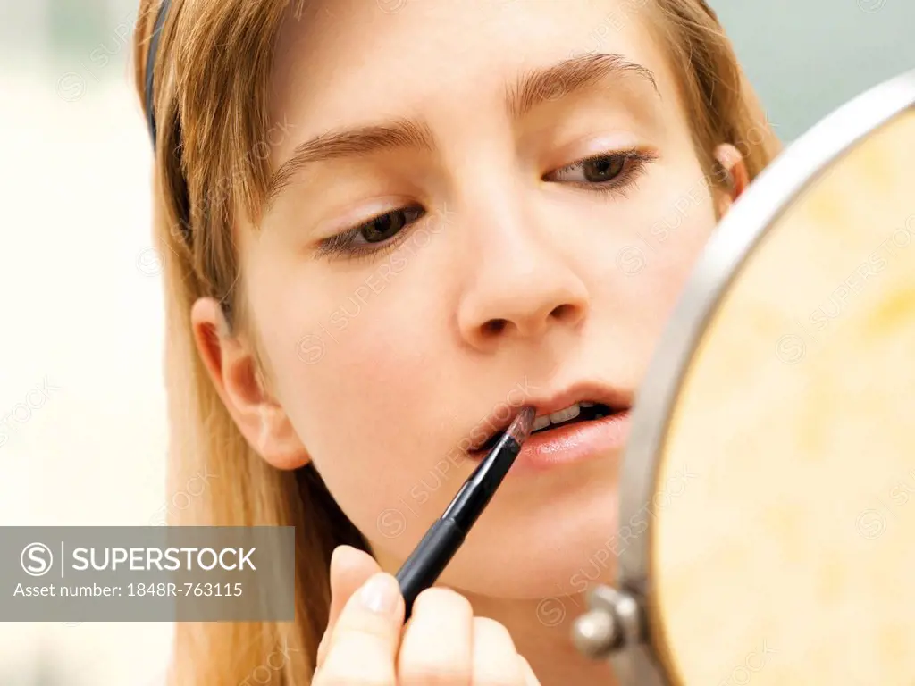 Young woman applying make-up, lip gloss