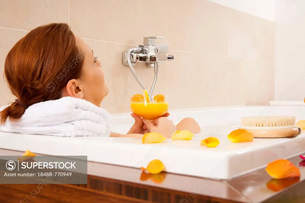 Woman taking a bath and drinking a juice