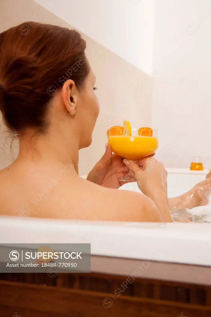 Woman taking a bath and drinking a juice