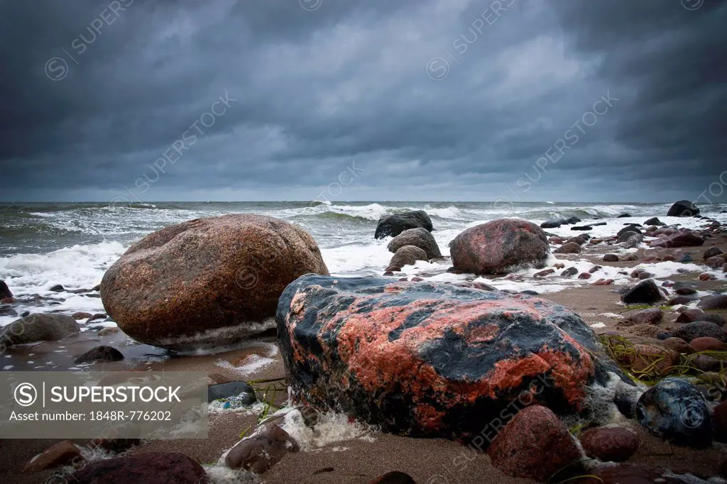 Reddish coloured boulders on the beach, a rough Baltic Sea at back, Rerik, Mecklenburg-Western Pomerania, Germany