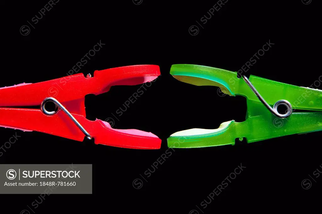 A red clothes-peg and a green clothes-peg are attacking each other, symbolic image for political power struggles
