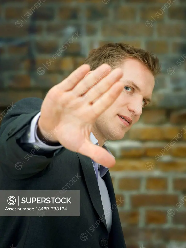 Businessman holding a hand up in a defensive manner